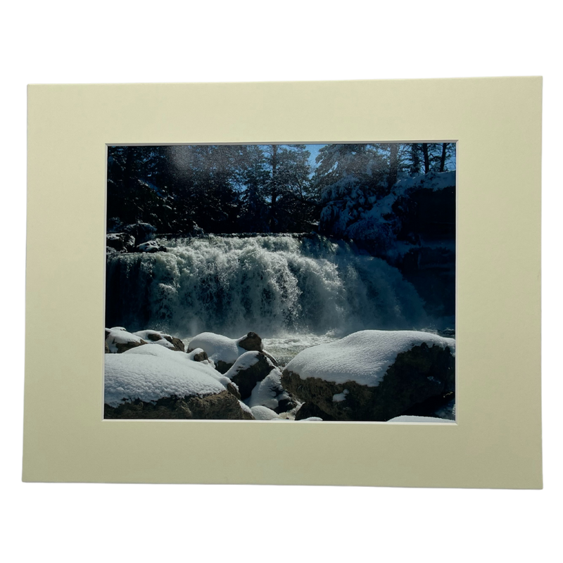 Photograph Of A Waterfall Behind Large, Snow-Covered Rocks With A Cream Colored Border