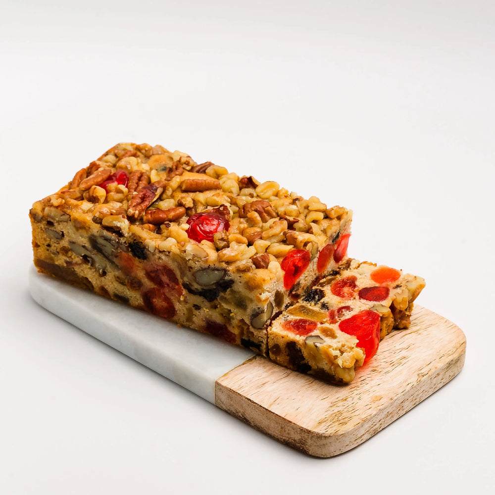 Loaf of fruitcake with a slice cut, on a white background