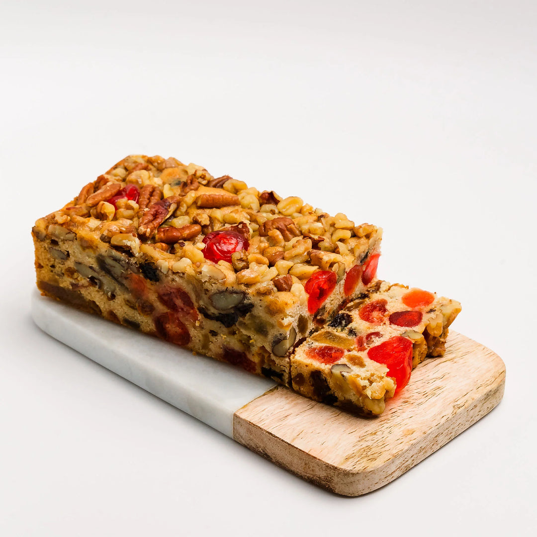 Loaf of fruitcake with a slice cut, on a white background