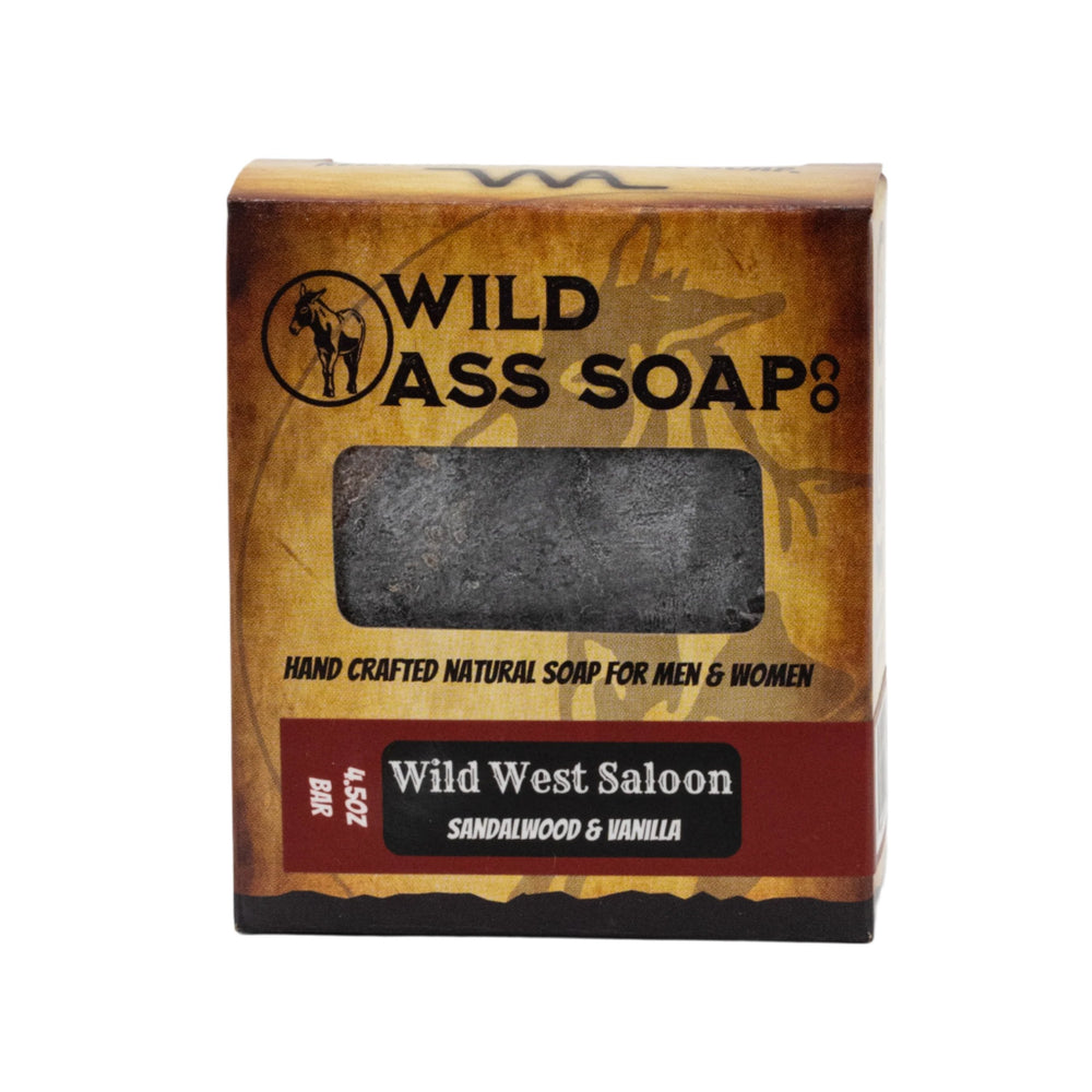A bar of soap with a rugged appearance, packaging that features the 'Wild Ass Soap Co' branding and text indicating the scent as 'Wild West Saloon' with sandalwood and vanilla.
