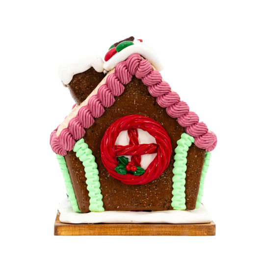 Decorative gingerbread house with pink and green icing on a white background