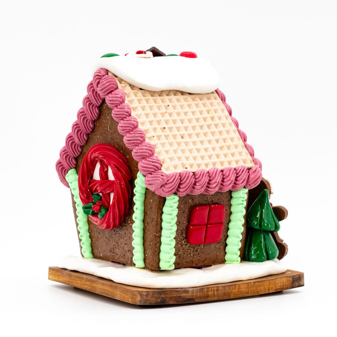 Decorative gingerbread house with pink roof and red door on a white background