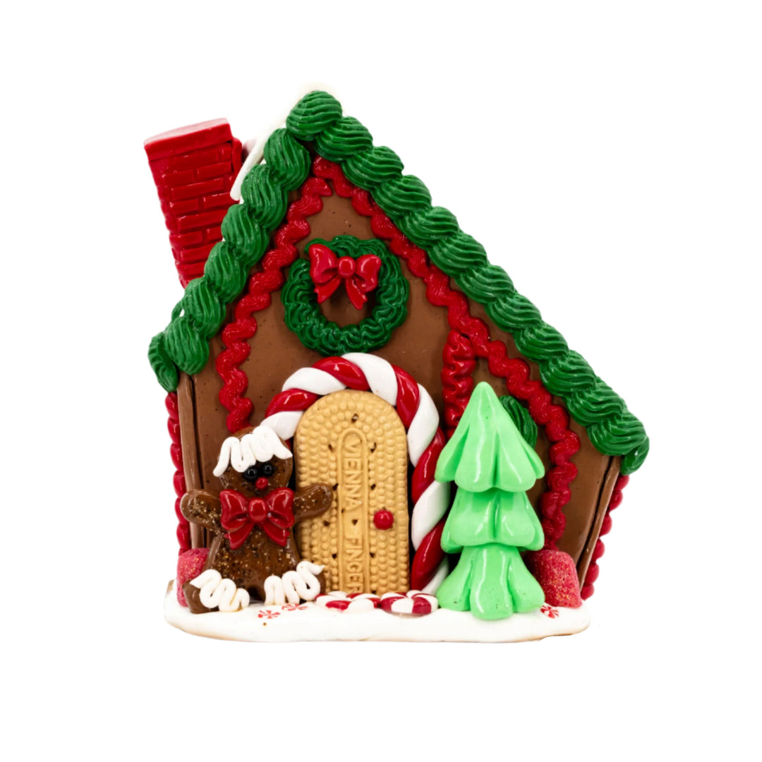 Decorative gingerbread house with red roof, green tree, and candy cane details on a white background