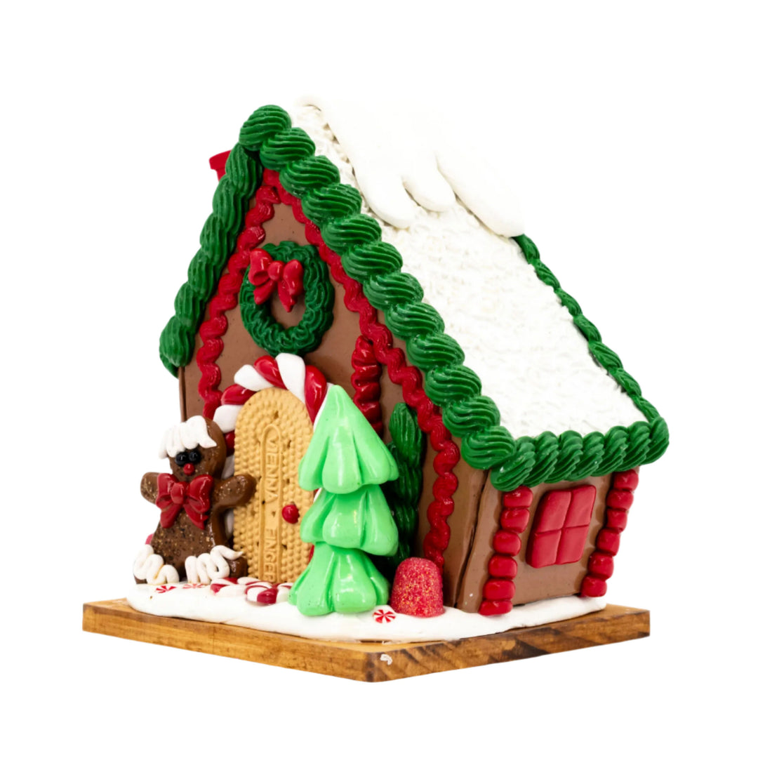 Decorative gingerbread house with a green roof and red accents on a white background