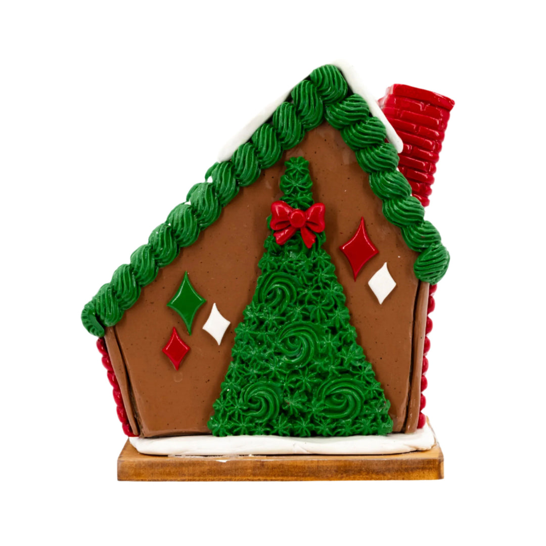 Decorative gingerbread house with green tree and red accents on a white background