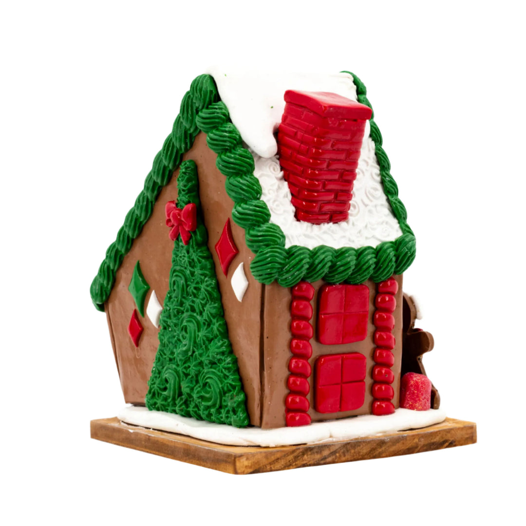 Gingerbread house with green roof, red windows, and a chimney on a white background