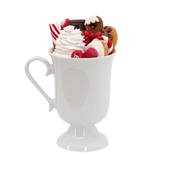 White mug filled with whipped cream, cookies, and candy on a white background