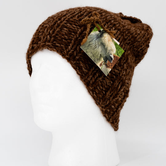A brown alpaca hat on a mannequin head with a tag showing an alpaca.