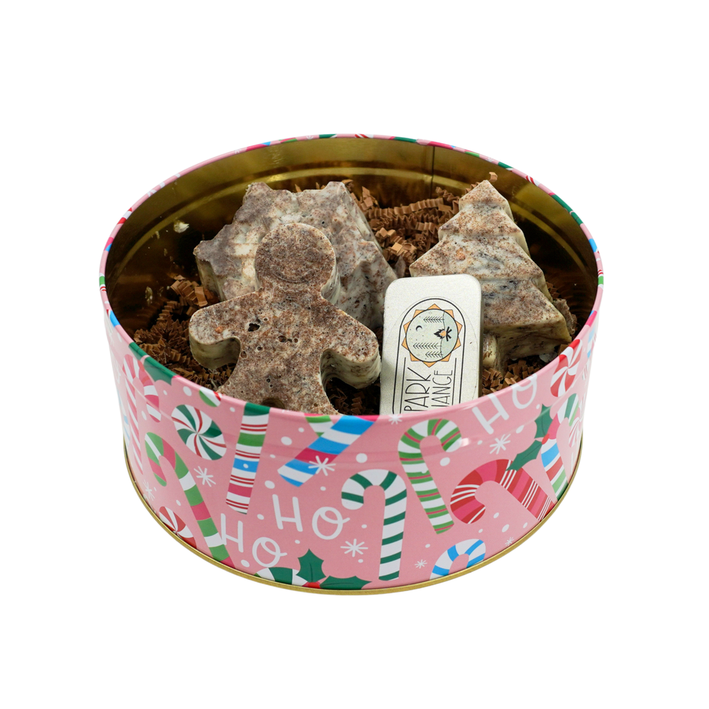 Decorative tin with Christmas-themed design containing pet treats and a small white card.