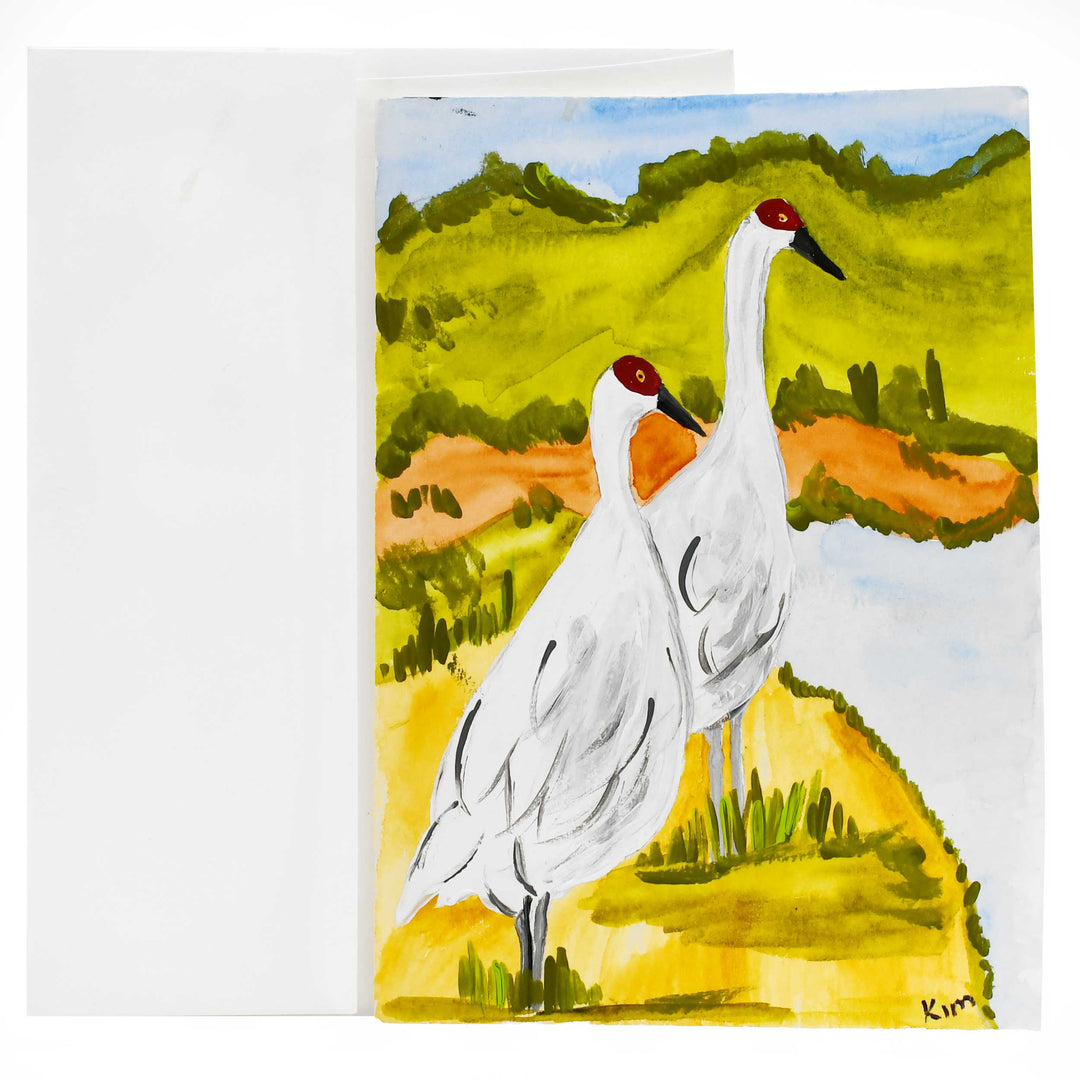 Painting of two cranes standing on a grassy field with a landscape background.
