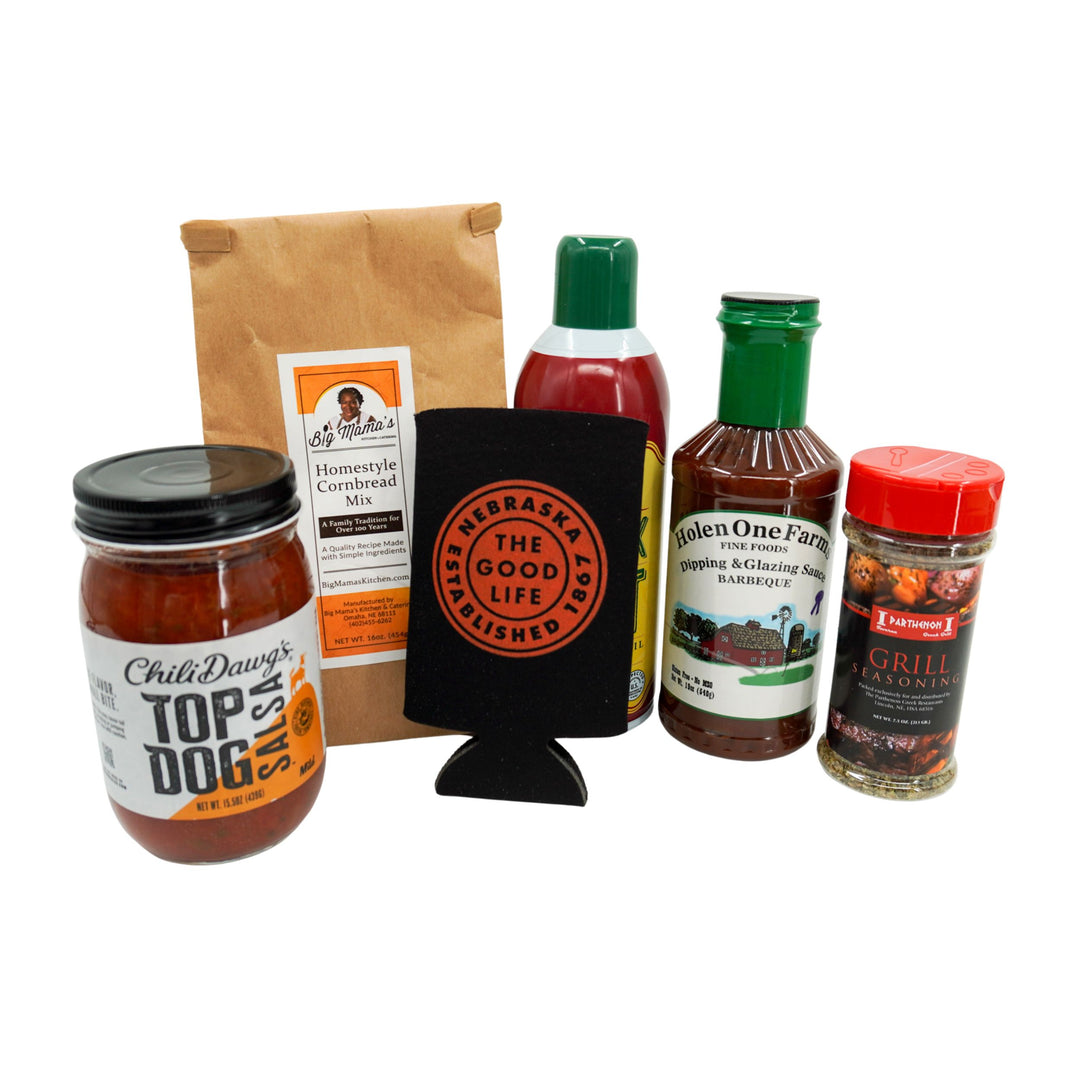 Collection of barbecue-related products including sauces, a can cooler, spices, duck fat, salsa and cornbread mix on a white background