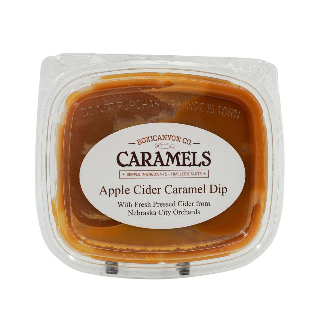 Apple cider caramel dip in a clear container with a label on a white background