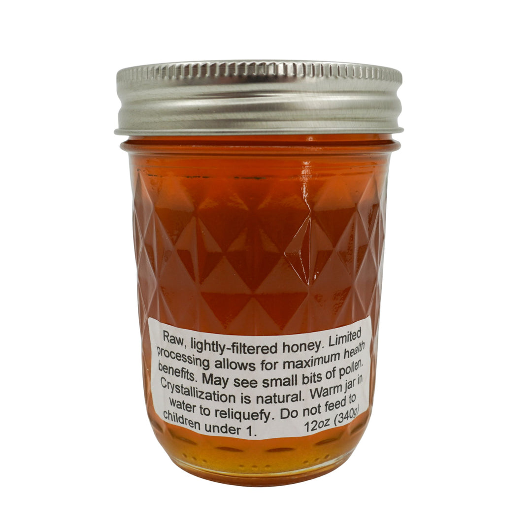 Jar of honey with a metal lid on a white background