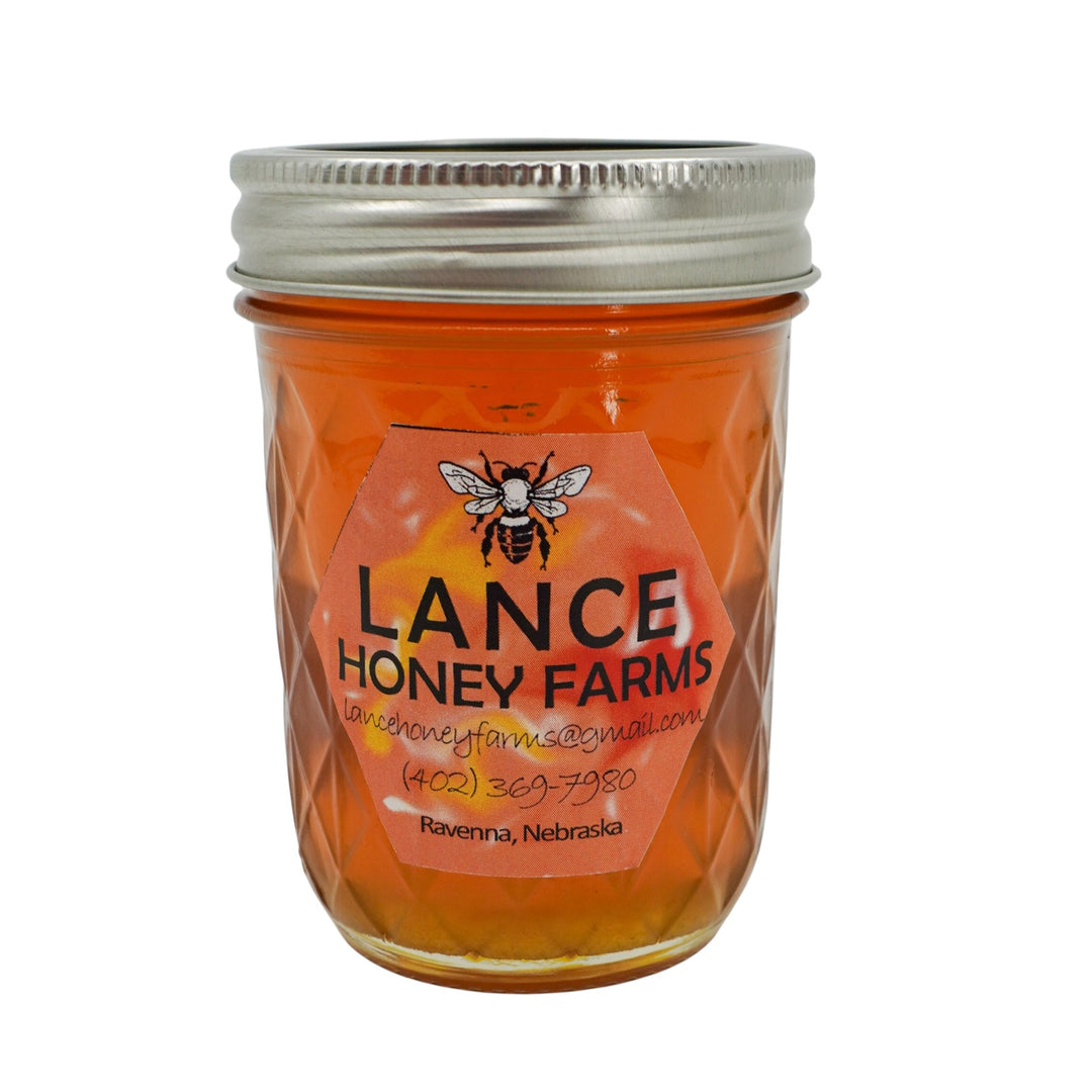 Jar of Lance Honey Farms honey with a silver lid on a white background