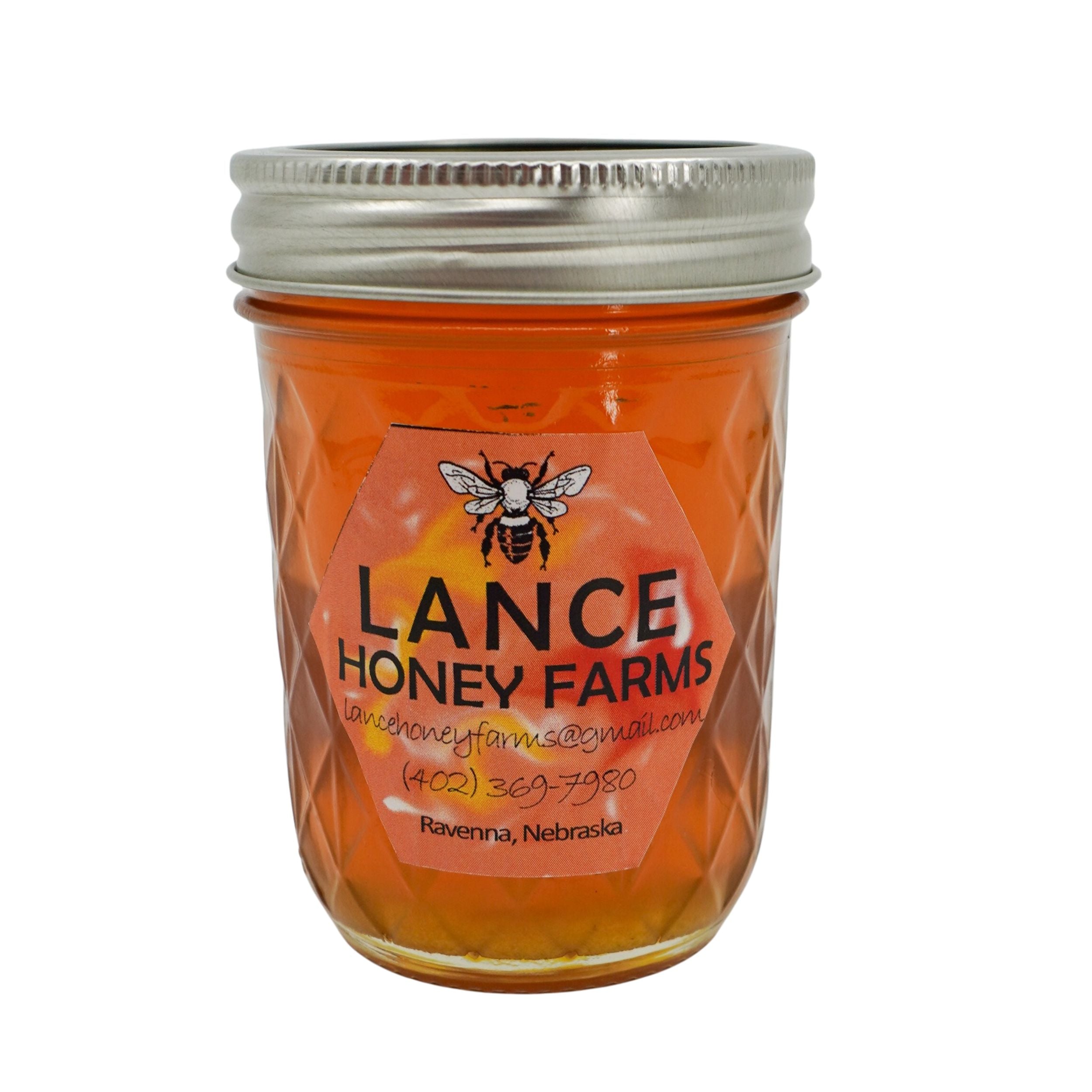 Jar of Lance Honey Farms honey with a silver lid on a white background