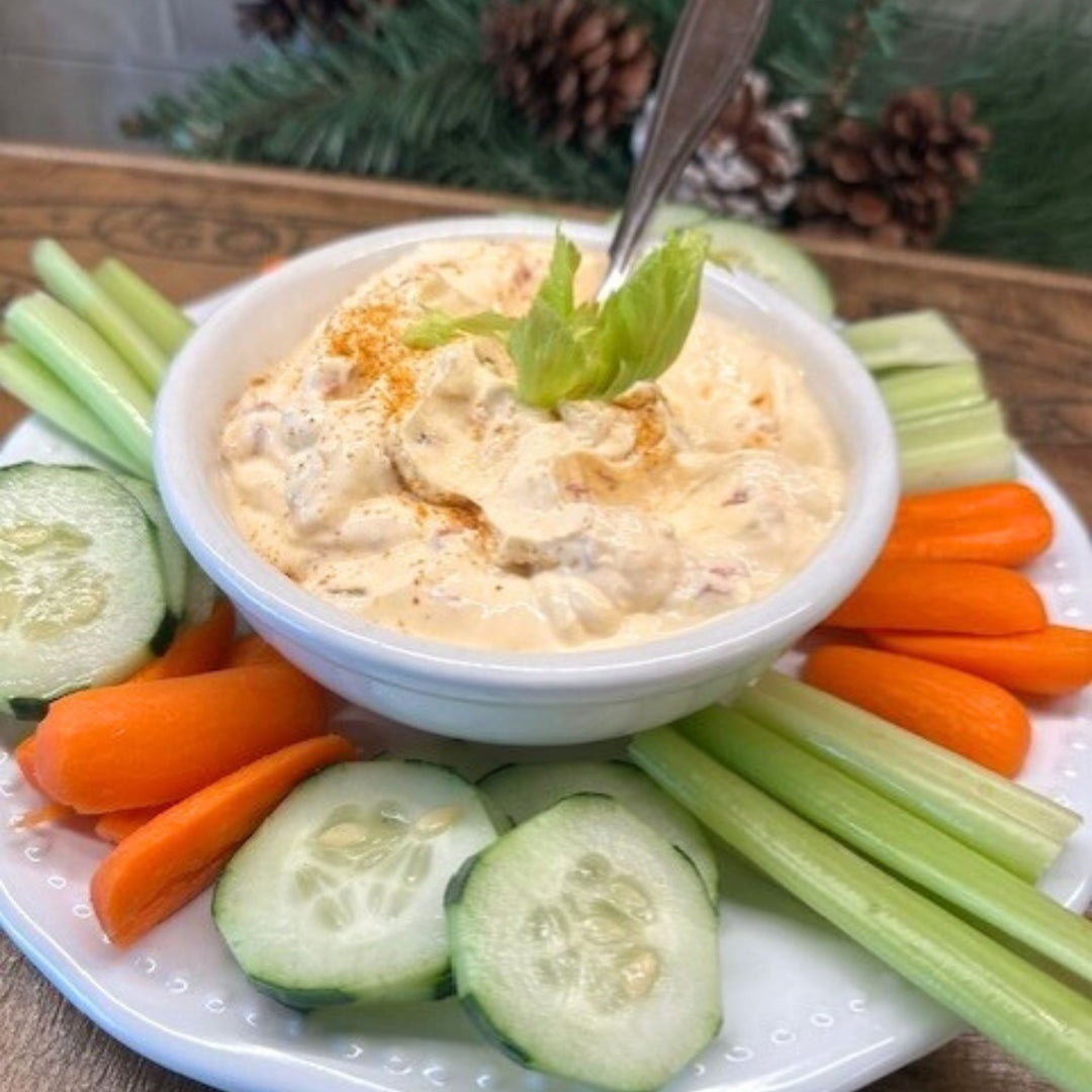 Bowl of dip with celery, carrots, and cucumbers on a platter.