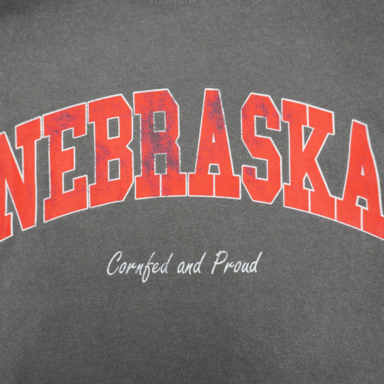 Gray t-shirt with red 'NEBRASKA' text and 'Cornfed and Proud' slogan on a gray background