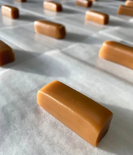 A row of freshly made caramels on parchment paper.