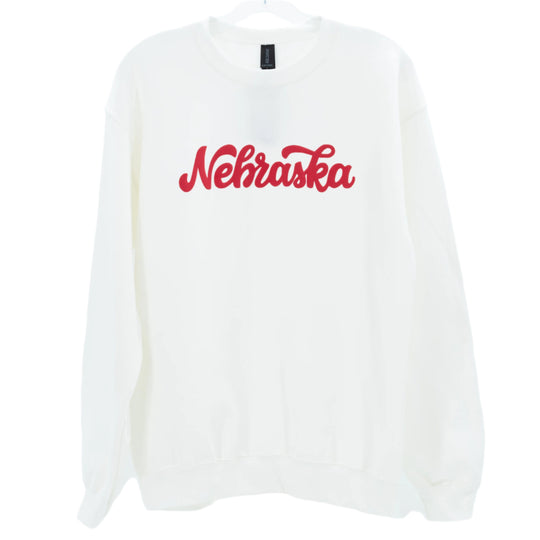 White crewneck sweatshirt with 'Nebraska' written in red script on the front.