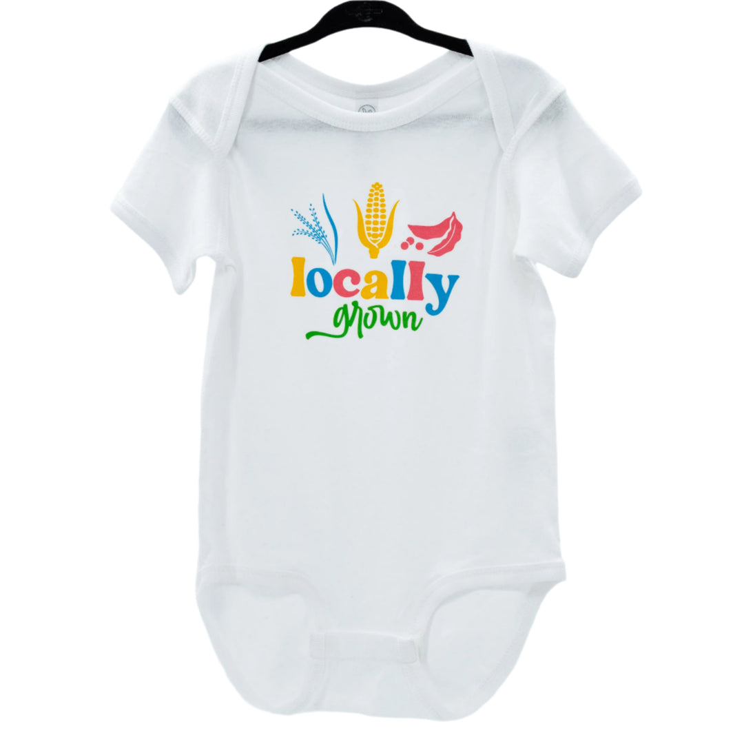 White infant onesie with 'Locally Grown' printed in colorful letters, accompanied by silhouettes of a corn stalk and tomato.