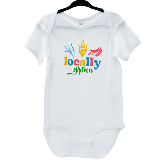 White infant onesie with 'Locally Grown' printed in colorful letters, accompanied by silhouettes of a corn stalk and tomato.