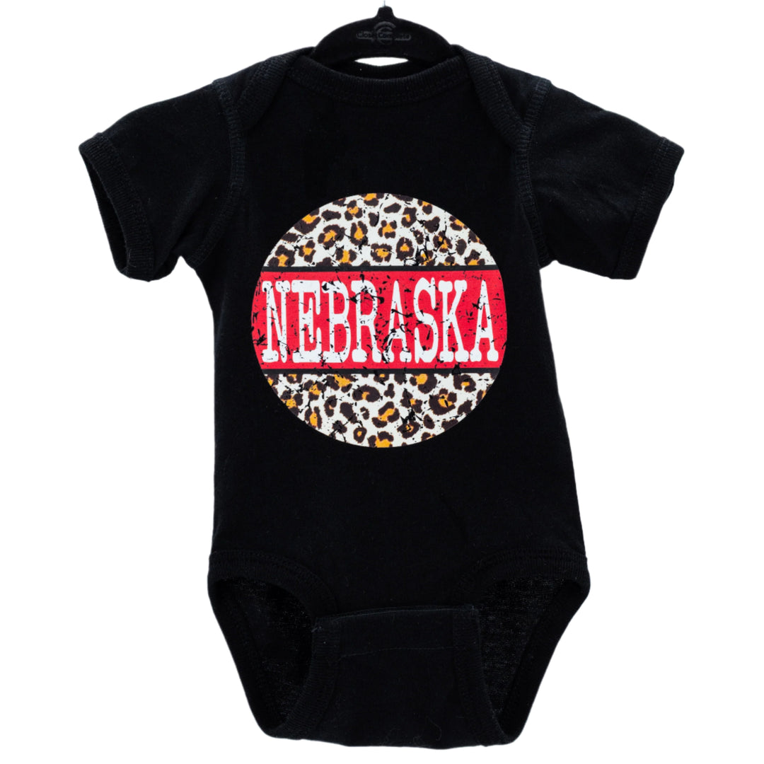 A black infant onesie with a cheetah print design and the word 'NEBRASKA' written across the center in red and white letters.