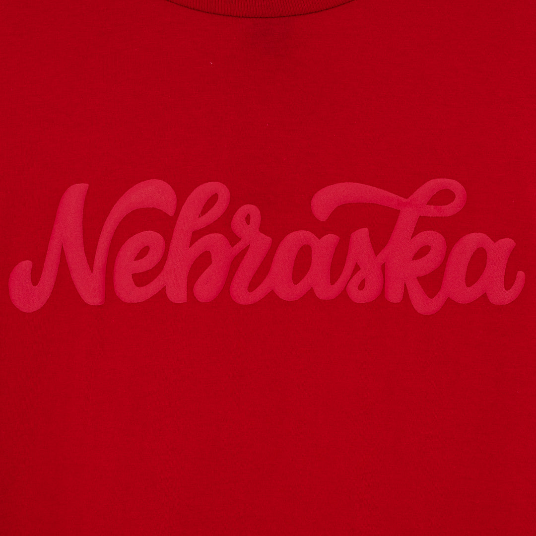 close up view of red cursive font on front of a red long-sleeve t-shirt.