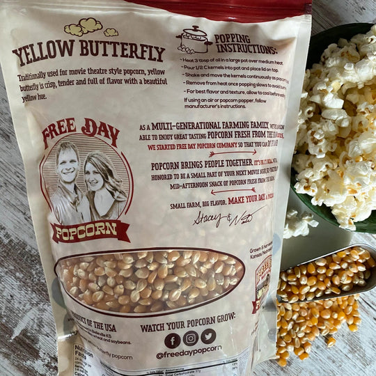 Yellow Butterfly Free Day Popcorn bag with popping instructions on a wooden surface.
