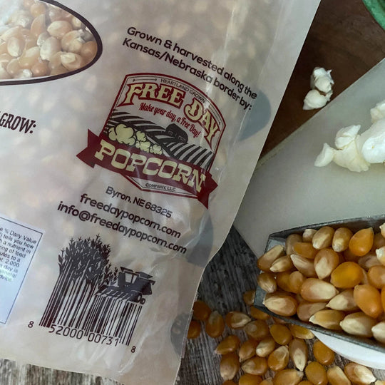 Free Day Popcorn bag with kernels and popcorn on a wooden surface