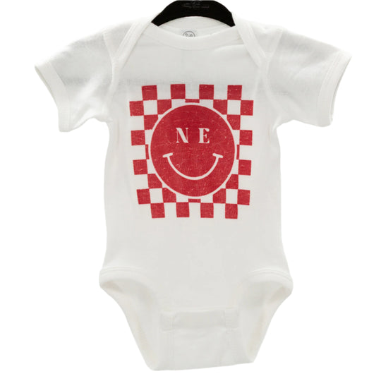 White infant one-piece with a red and gray checkered design and a smiley face in the center, with the letters 'NE' on the top left.