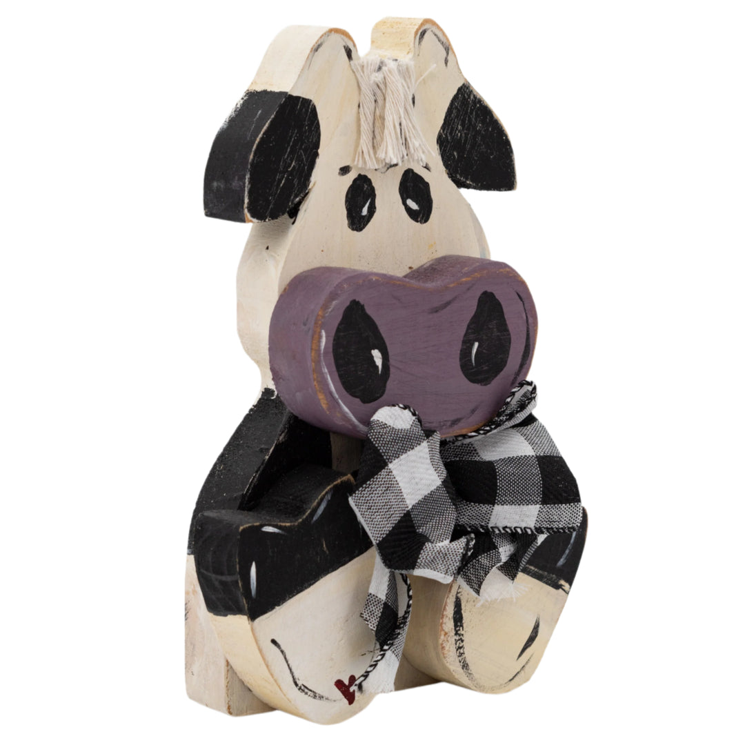 Wooden cow figurine with a purple heart and plaid ribbon on a white background