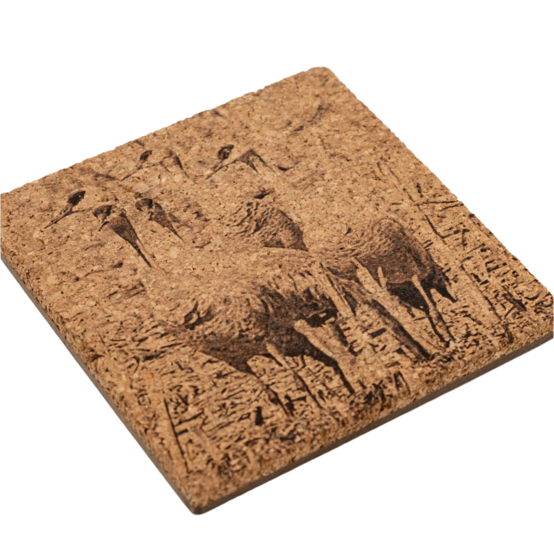 Cork coaster with embossed design of sandhill cranes on a white background.