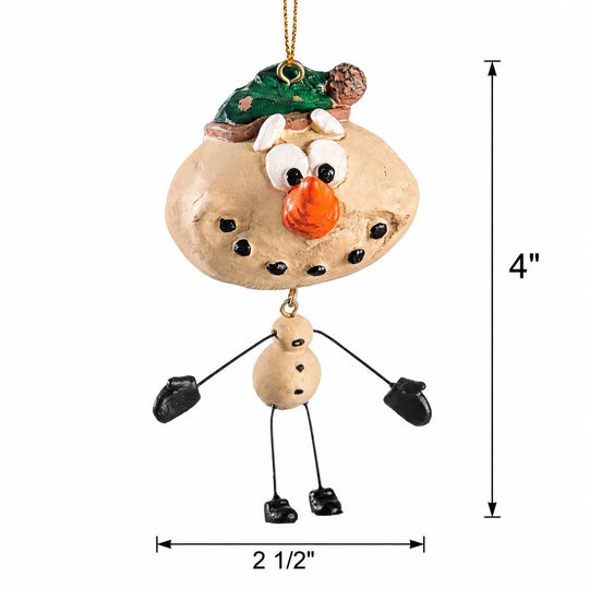A whimsical snowman ornament made from a beige stone face and body, with black wire limbs, black mittens, an orange nose, white eyes, a green hat, and a small brown pinecone accent. Black dimension lines on a white background show the ornament is 4 inches tall and 2 1/2 inches wide.
