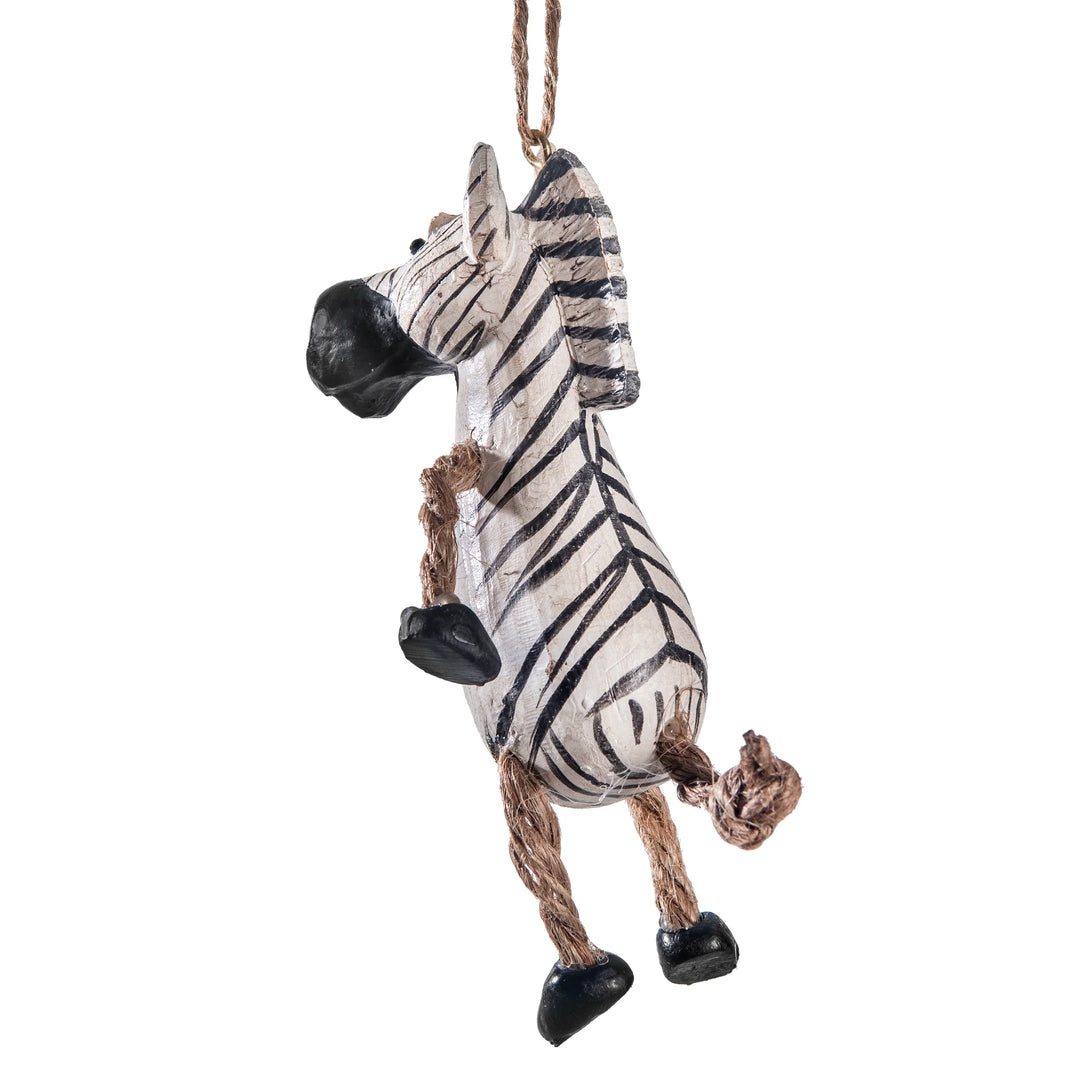 A hanging zebra figurine with a white body, black stripes, black hooves and nose, and a brown rope tail and hanging loop, shown on a plain white background.