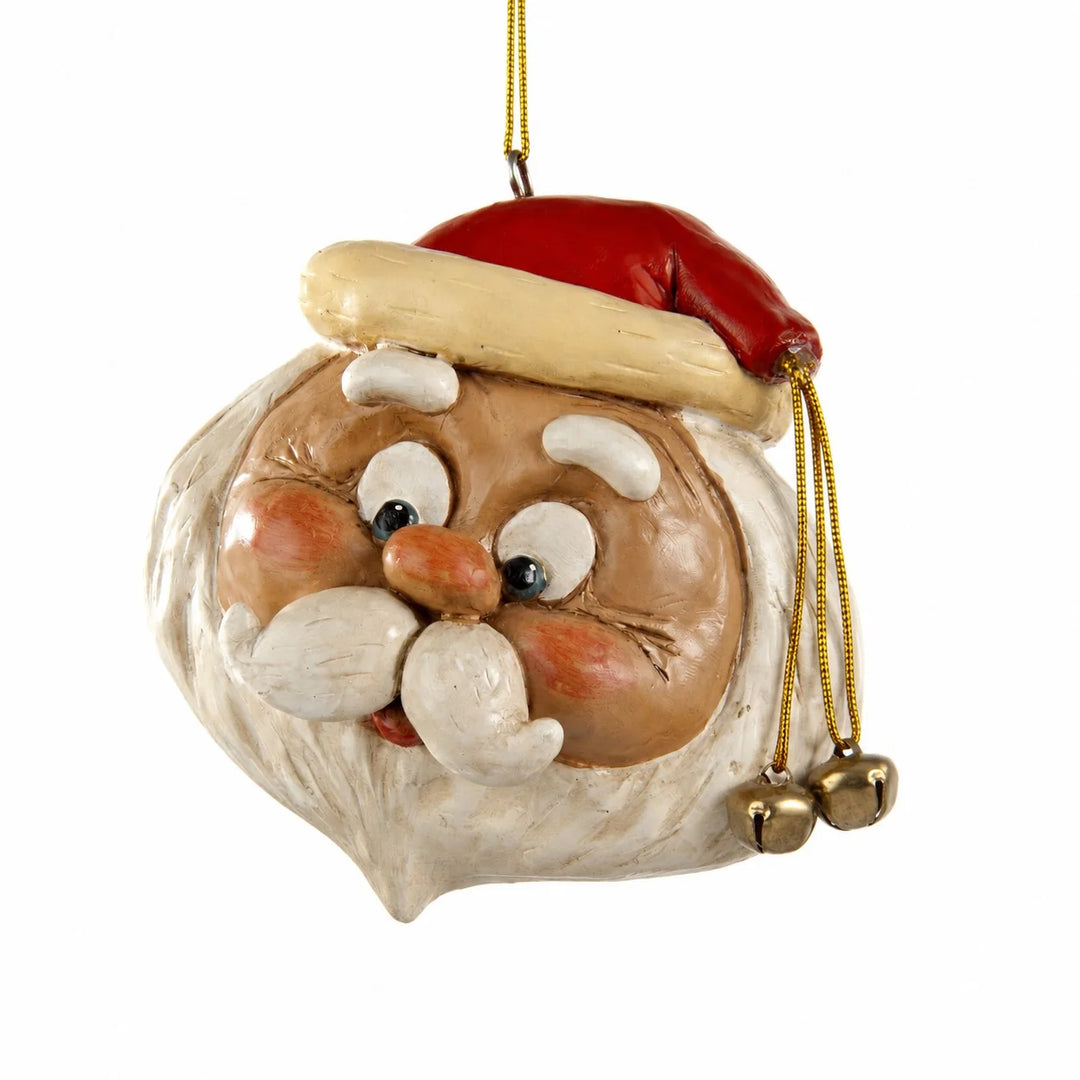A hand-painted Christmas ornament shaped like Santa Claus' head, featuring a red hat with a beige trim, a brown face, white beard, and gold hanging cord with small bells.