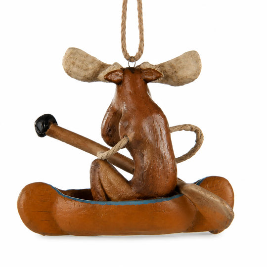 A carved wooden moose ornament sitting in a canoe and holding a paddle, hanging by a rope on a white background.