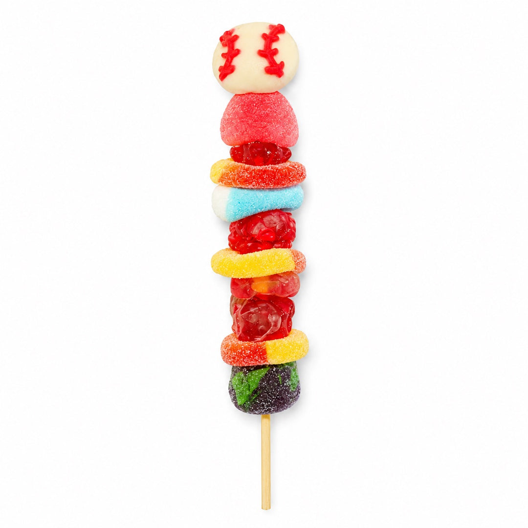 Baseball candy kabob topped with a baseball gummy and stacked with assorted gummy candies on a wooden skewer, isolated on a white background.