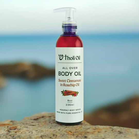 Bottle of Tholi Oil body oil on a rock with a blurred natural background