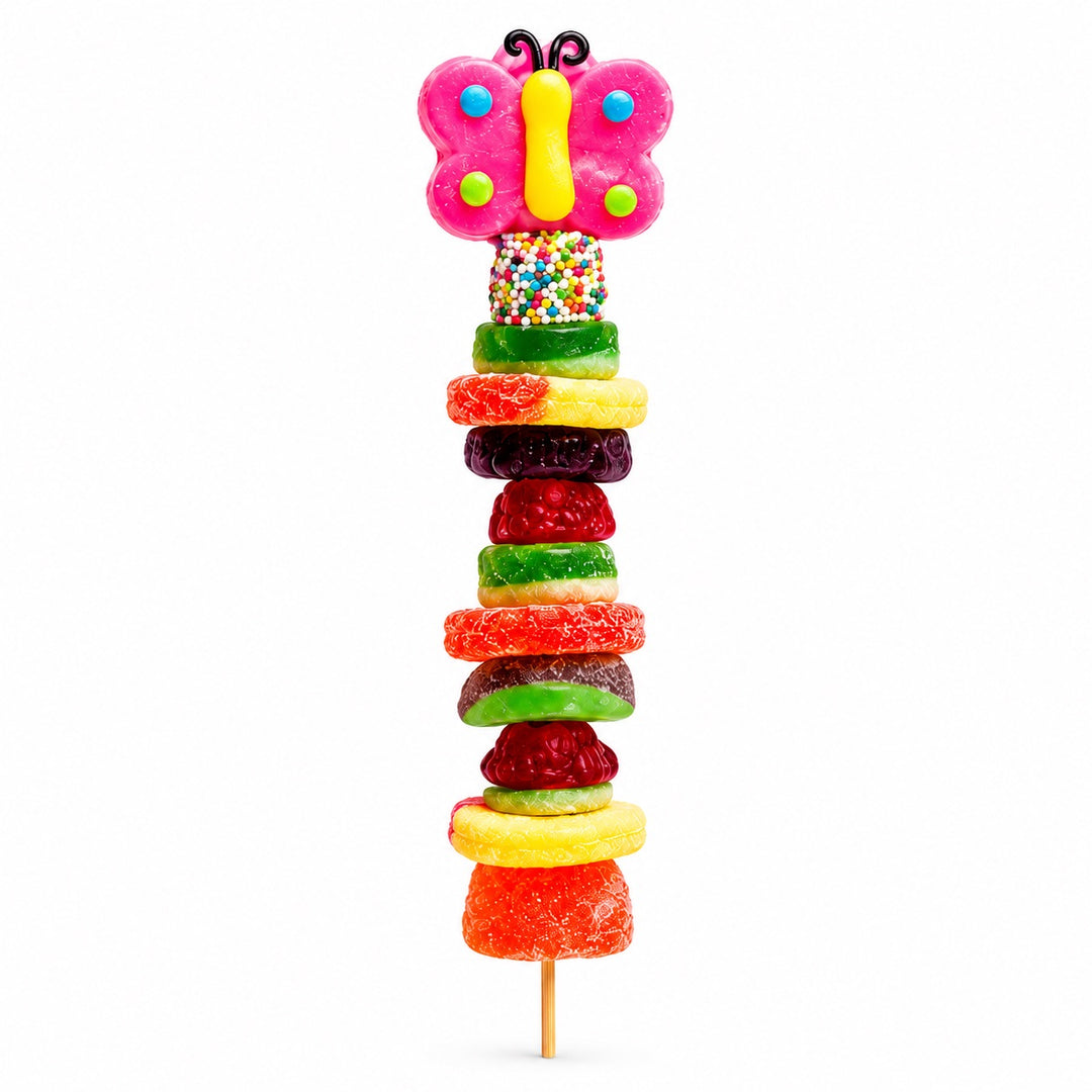 Butterfly candy kabob with a pink butterfly gummy topper and assorted fruit-flavored gummies on a wooden skewer, isolated on a white background