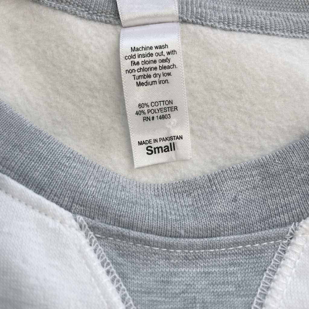 Clothing label on a gray shirt with washing instructions and material details.