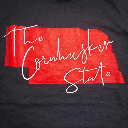 Black t-shirt with red outline of Nebraska and 'The Cornhusker State' text.