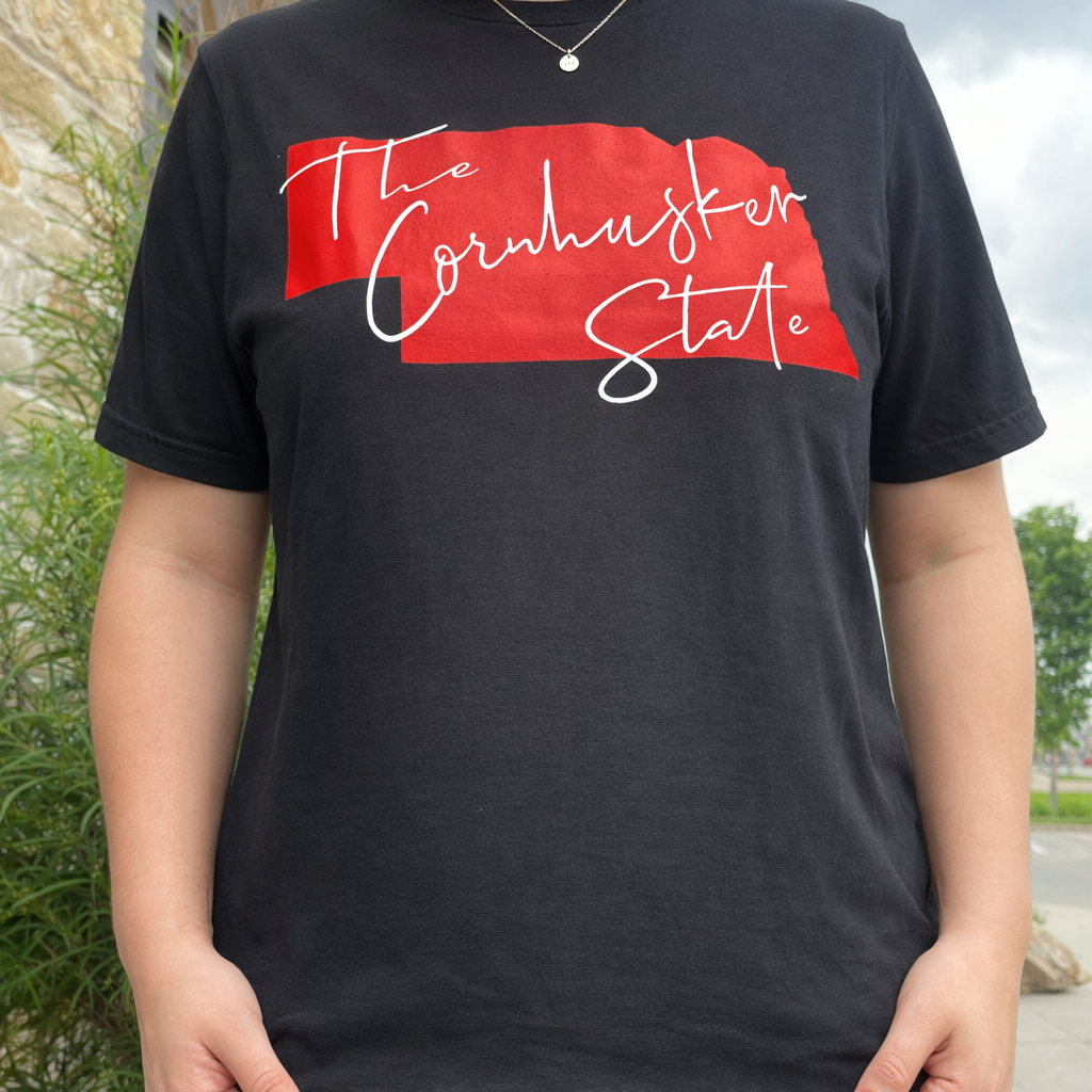 Person wearing a black t-shirt with a red and white graphic design outdoors.