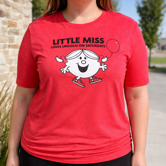 Person wearing a red t-shirt with a cartoon character and text, standing outdoors.