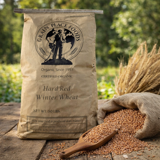 Bag of Grain Place Foods Hard Red Winter Wheat with wheat grains and a scoop on a wooden surface.