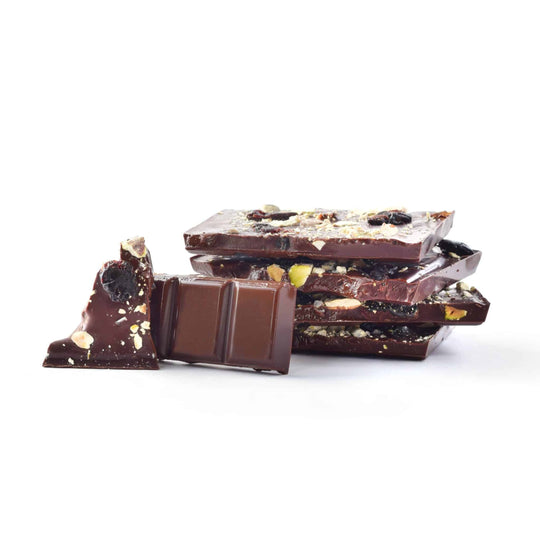 Dark chocolate bars with pistachios and cherries on a white background
