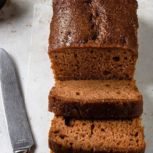 Loaf of chocolate merlot bread sliced into pieces with a knife on a light surface