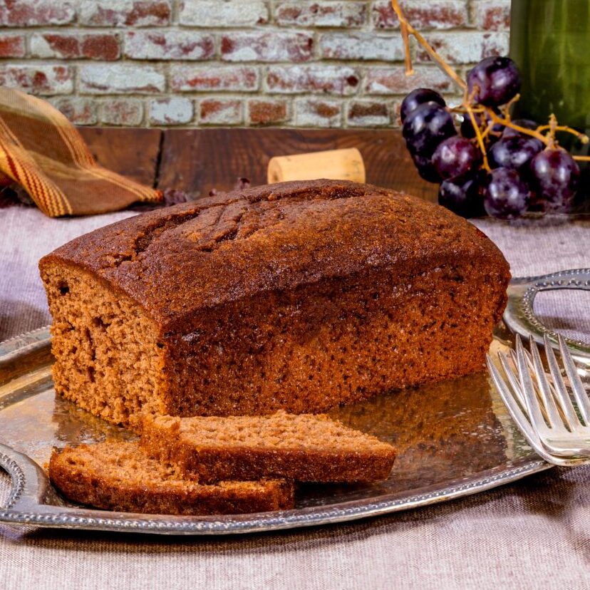 Loaf of chocolate merlot bread on a silver platter with grapes in the background