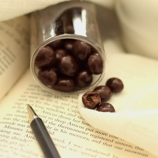chocolate covered coffee beans on an open book with a pen