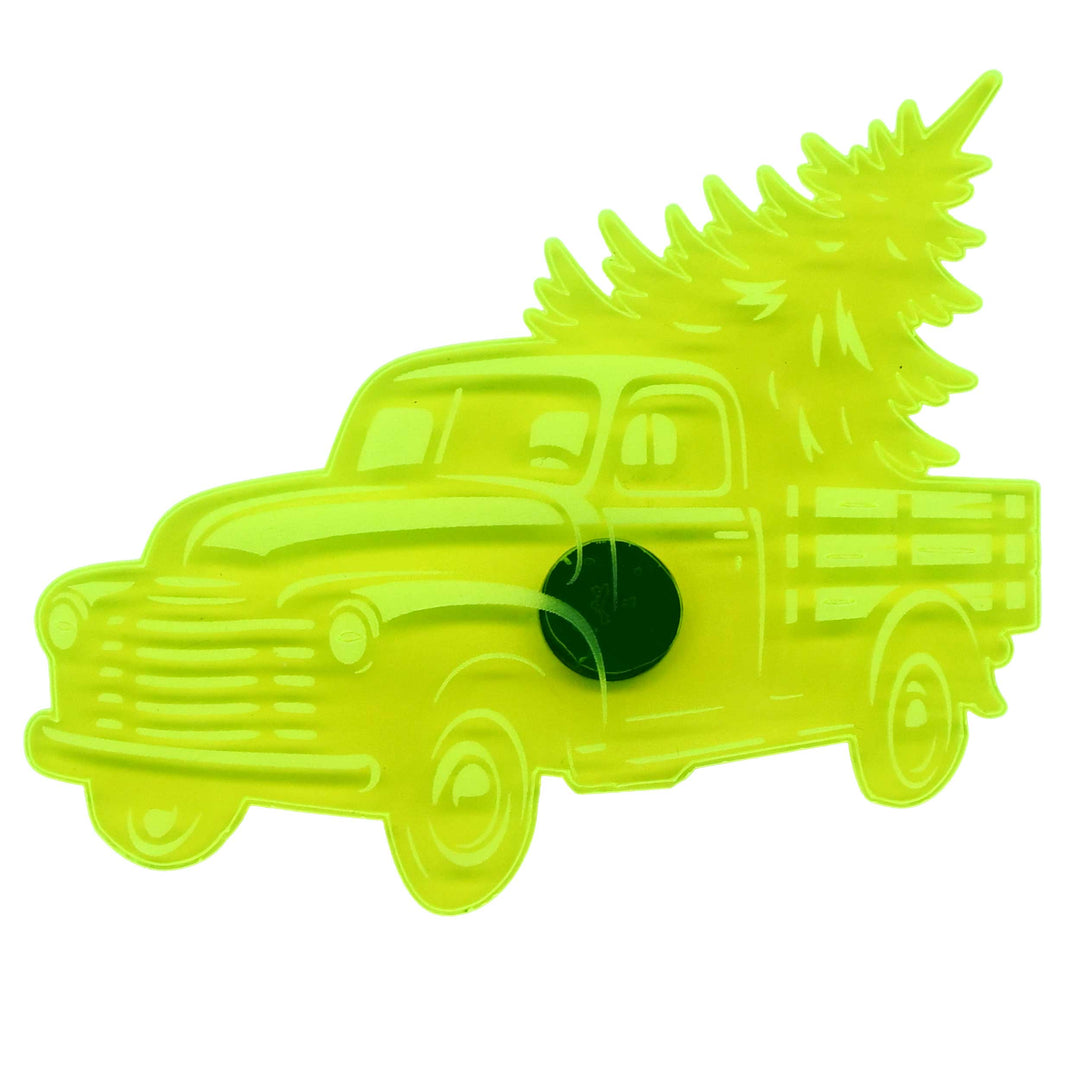 A bright neon yellow-green translucent plastic pin shaped like a vintage pickup truck carrying a Christmas tree, isolated on a white background.
