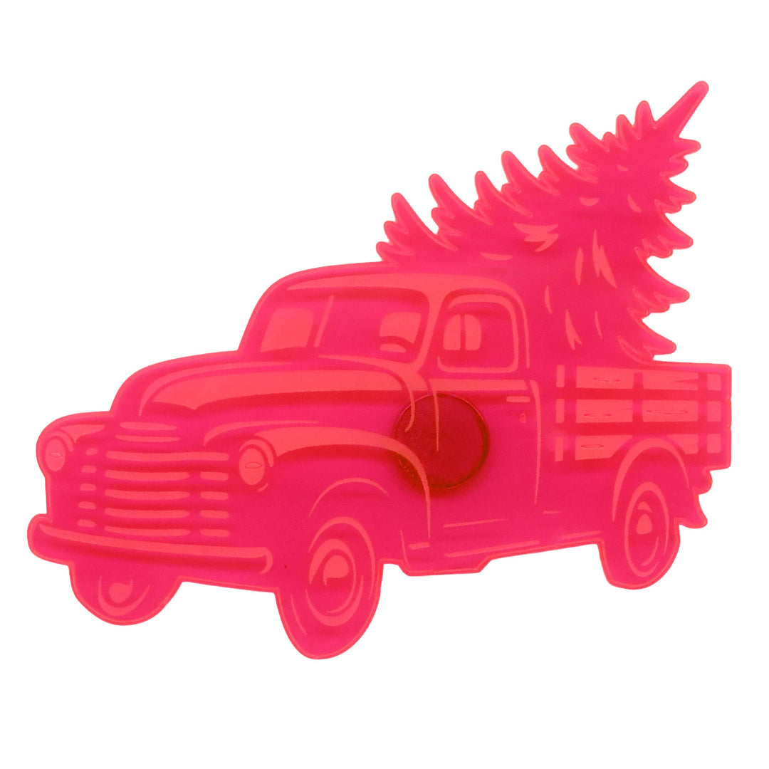 A bright pink plastic cookie cutter shaped like a vintage pickup truck carrying a Christmas tree, isolated on a white background.